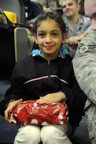 Yosra Hikal, sitting next to her mentor Senior Airmen Robert Gibson, smiles as she waits to open the present she received during a tour at Joint Base Charleston-Air Base Dec. 8. JB Charleston's Airmen Leadership School invited more than 30 third grade students from Memminger Elementary School to tour the base. The tour is part of an on-going community service project, to bring awareness to the opportunities the Air Force has to offer future generations. Gibson is from the 628th Security Forces Squadron. (U.S. Air Force photo/Airman 1st Class Ashlee Galloway)