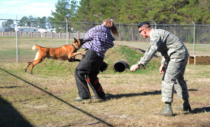 Staff Sgt. Timothy Garrett motions Akim, a military working dog, to attack Staff Sgt. Craig Martin during a military working dog demonstration at Joint Base Charleston-Air Base Dec. 8. JB Charleston's Airmen Leadership School invited more than 30 third grade students from Memminger Elementary School to tour the base. The tour is part of an on-going community service project to bring awareness to the opportunities the Air Force has to offer future generations. Garrett and Martin ae from the 628th Security Forces Squadron. (U.S. Air Force photo/Airman 1st Class Ashlee Galloway)
