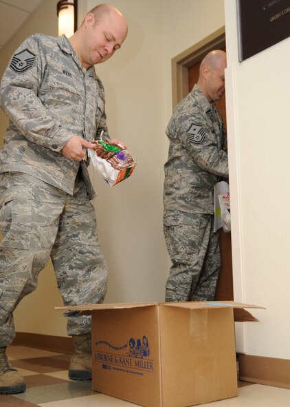 MINOT AIR FORCE BASE, N.D. – Master Sgt. David West (left), 5th Communication Squadron chief of quality assurance and training, and Master Sgt. Patrick Lund, 5th Force Support Squadron first sergeant, deliver donated Christmas cookies to Minot Airmen currently living in the dormitories here, Dec. 9. The Airman Cookie Drive is an annual event which helps boost the morale of young Airmen far from home during the holidays. This year cookies were gathered from on and off base. After cookies are gathered and divided into bags, Minot first sergeants pass the cookies out to the dormitory Airmen. (U.S. Air Force photo/Senior Airman Ashley N. Avecilla)