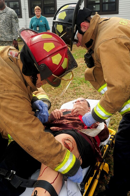 Fort Eustis firefighters strap Monica White, a Mission Installation Contracting Command procurement analyst, onto a gurney during an active shooter exercise Dec. 6. The exercise analyzed first responders' capabilities in mitigating emergencies and contingencies affecting Fort Eustis. (U.S. Air Force photo by Staff Sgt. Ashley Hawkins/Released)
