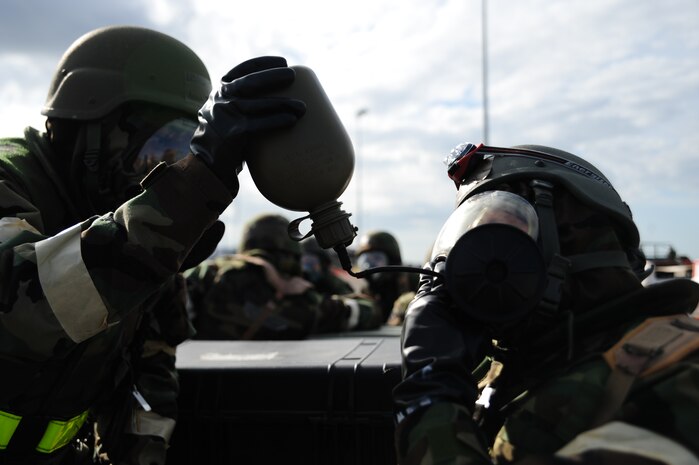 Airmen assist one another in consuming water while in chemical gear during the Operational Readiness Inspection at Gulfport, Miss. Dec. 3, 2011. More than 600 Airmen simulated a deployment which tested basic Airman knowledge, such as Self Aid Buddy Care and Chemical Biological Radioactive Nuclear and Explosive responses among many others. (U.S. Air Force photo/Staff Sgt. Katie Gieratz)(Released)