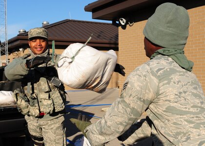 Senior Airman Christopher Bryant tosses a sandbag to Senior Airman Tony Kinch-Rice during the Operational Readiness Inspection at Gulfport, Miss. Dec. 2, 2011.  Airmen simulated a deployment for the ORI which tested basic Airman knowledge, such as Self Aid Buddy Care and Chemical Biological Radioactive Nuclear and Explosive responses among many others. Both Bryant and Kinch-Rice are patrolmen with the 628th Security Forces Squadron. (U.S. Air Force photo/Staff Sgt. Katie Gieratz)(Released)