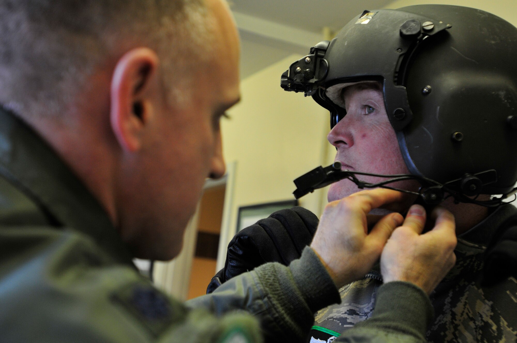 ROYAL AIR FORCE LAKENHEATH, England – Lt. Col. Brad Dow, 56th Rescue Squadron commander, assists Lord Edward Iveagh, the Right Honourable Earl of  Iveagh, Deputy Lieutenant and 56th RQS honorary commander, with his helmet at the 56th RQS headquarters, Dec. 8, 2011. Iveagh visited the 56th RQS to receive a flight in a HH-60G Pave Hawk and familiarize himself with the 56th RQS mission. (U.S. Air Force photo by Senior Airman Tiffany M. Deuel)