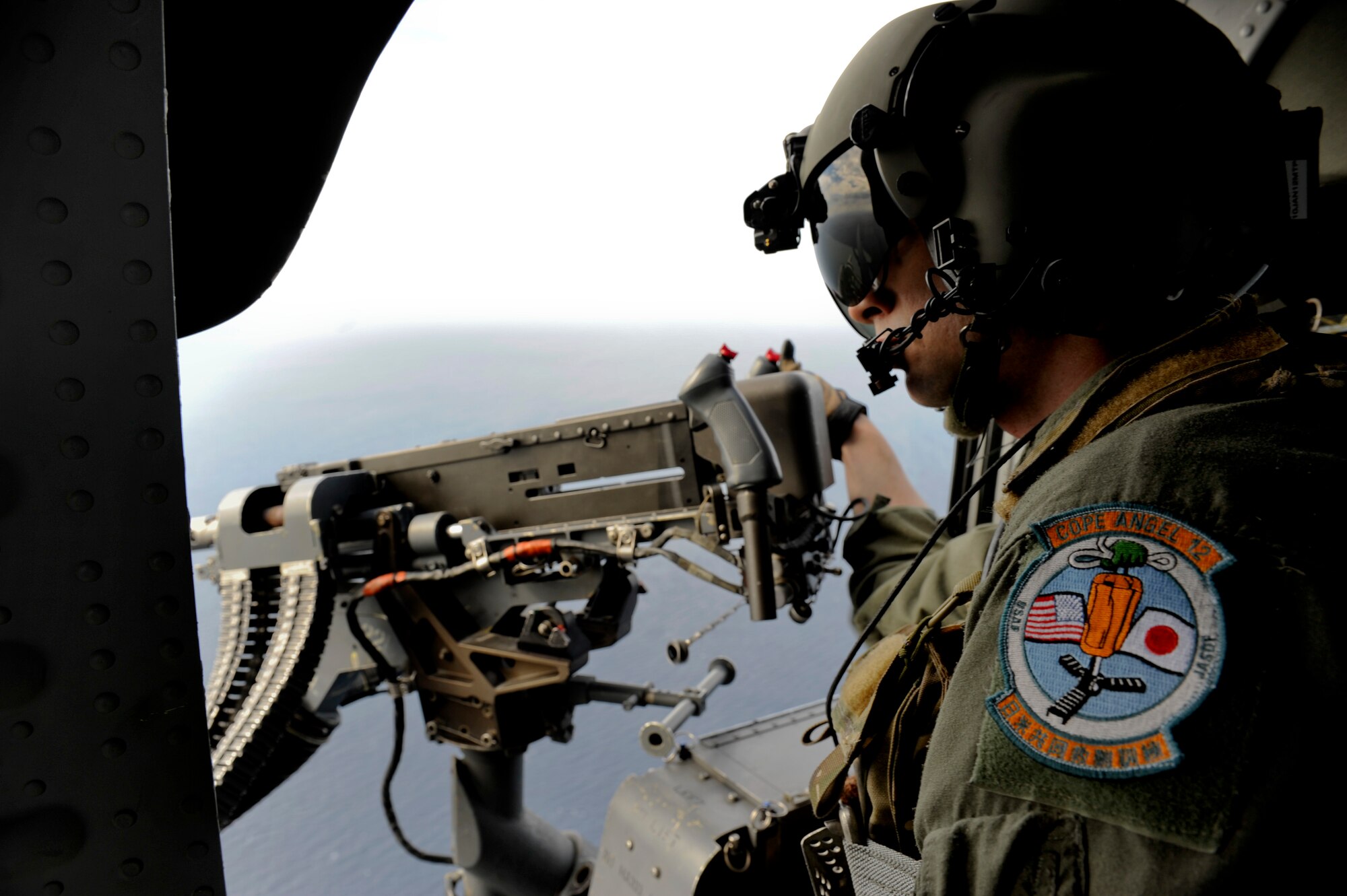 U.S. Air Force Staff Sgt. Thomas Seffernick, 33rd Rescue Squadron gunner, scans the sea from the door of a U.S. Air Force HH-60G Pave Hawk helicopter as it flies over the Pacific Ocean near Okinawa, Japan, in support of Cope Angel 12 Dec. 7, 2011. Cope Angel 12 was an exercise from Dec. 5 to 8 that gave pararescuemen from the Japan Air Self Defense Force and U.S. Air Force the opportunity to train together on procedures during a simulated earthquake on the island. (U.S. Air Force photo by Airman 1st Class Maeson L. Elleman/Released)