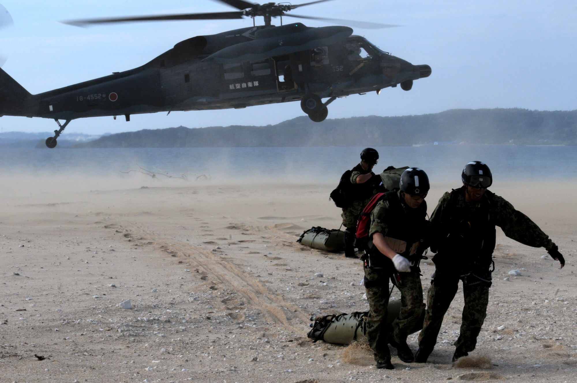 Japan Air Self Defense Force pararescuemen drag rescue sleds with equipment away from a JASDF UH-60J Rescue Wings helicopter during Cope Angel 12 in Okinawa, Japan, Dec. 5, 2011. During Cope Angel, JASDF members teamed up with Kadena's 33rd and 31st Rescue Squadrons to increase bilateral readiness in the region. (U.S. Air Force photo by Airman 1st Class Maeson L. Elleman/Released)