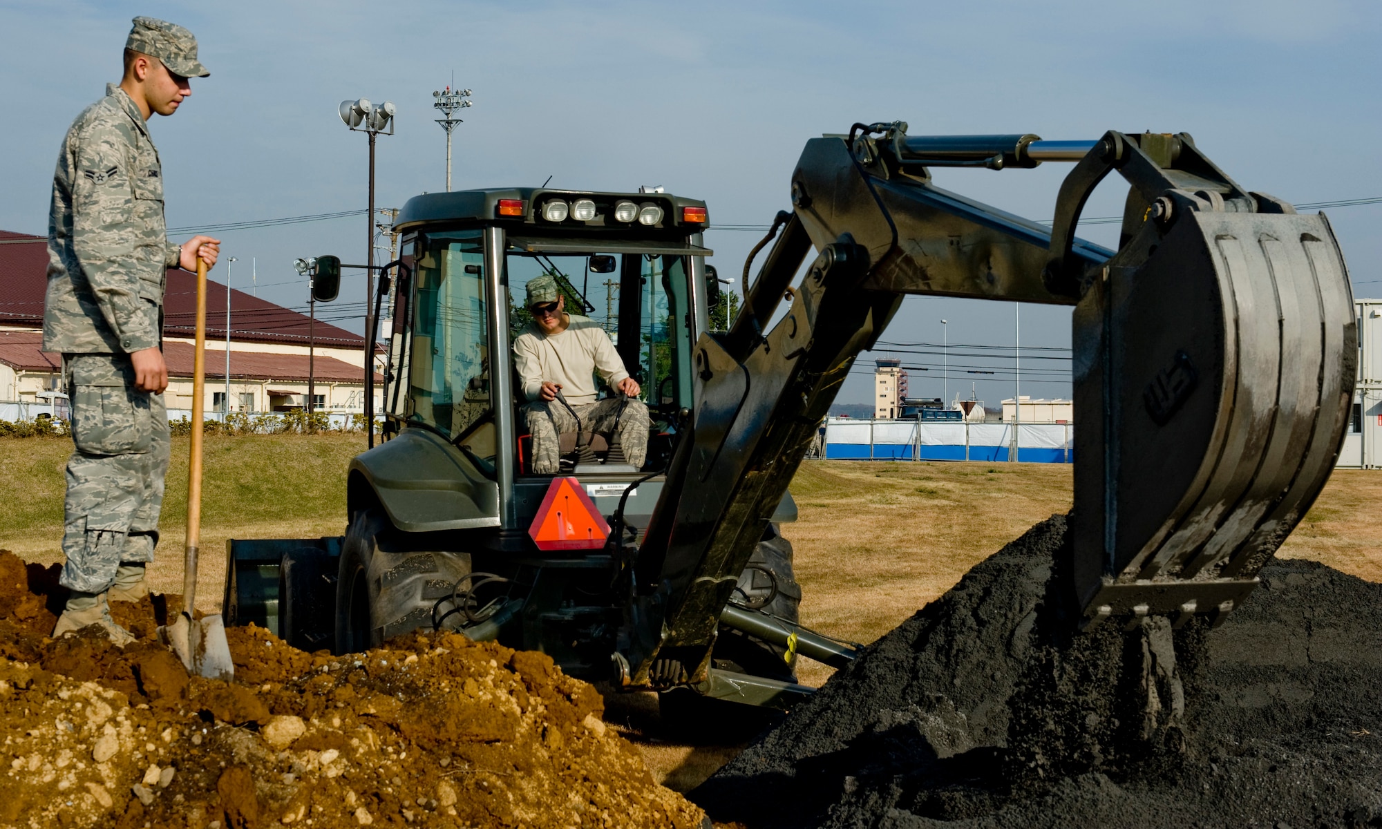 YOKOTA AIR BASE, Japan -- (Left to right) Airman 1st Class Matthew Chance and Airman 1st Class Paul Scheck, both 374th Civil Engineer Squadron pavement and equipment technicians, cover a hole containing a World War II era unexploded ordnance with sand at Yokota Air Base, Japan, Dec. 7, 2011. The UXO was discovered at a construction site on base and was detonated by a Commander Fleet Activities Yokosuka, Japan, explosive ordnance disposal team after being covered with wood, sandbags and sand to suppress the blast. (U.S. Air Force photo/Airman 1st Class John D. Partlow)