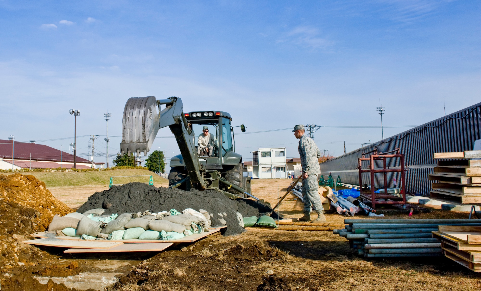 YOKOTA AIR BASE, Japan -- (Left to right) Airman 1st Class Paul Scheck and Airman 1st Class Matthew Chance, 374th Civil Engineer Squadron pavement and equipment technicians, cover a hole containing a World War II-era unexploded ordnance with sand at Yokota Air Base, Japan, Dec. 7, 2011. The UXO was discovered Dec. 6, 2011, at a construction site and detonated by an explosive ordnance team from Commander Fleet Activities Yokosuka, Japan, after being covered with wood, sandbags and sand to suppress the blast. (U.S. Air Force photo/Airman 1st Class John D. Partlow)