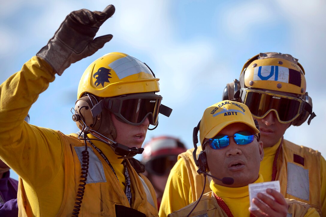 U.S. Navy Senior Chief Petty Officer Terry Libed, center, instructs Petty Officer 3rd Class Eric Welsh during flight deck firefighting drills aboard the aircraft carrier USS Carl Vinson under way in the Pacific Ocean, Dec. 7, 2011. Libed and Welsh are aviation boatswain's mates, handling.