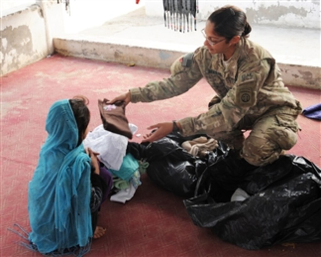 U.S. Navy Petty Officer 1st Class Rachael Bradley, with the Kandahar Provincial Reconstruction Team, hands out winter clothes to a girl during a visit to the women and children sections of Sarposa Prison in Kandahar, Afghanistan, on Dec. 3, 2011. The Kandahar Provincial Reconstruction Team is a civilian-military organization whose mission is to improve security, governance and infrastructure capacity throughout Kandahar province.  