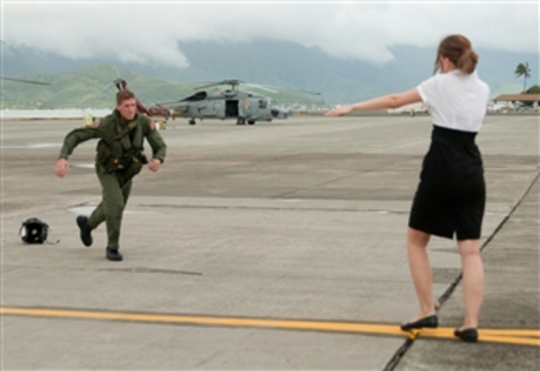 U.S. Navy Petty Officer 2nd Class Christopher Warren, with Detachment 4, Helicopter Anti-Submarine Squadron Light 37, drops his helmet and runs to greet his wife in Kaneohe, Hawaii, on Dec. 1, 2011.  Detachment 4 returned from a six-month deployment aboard the guided missile destroyer USS Chung Hoon (DDG 93).  