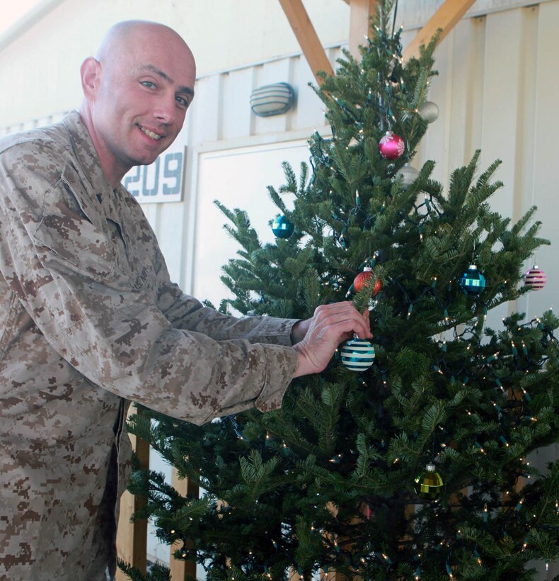 Commander Christopher Fronk, division chaplain, hangs an ornament on a tree to get in the Christmas spirit.  (Official U.S. Marine Corps photo by Cpl. Thomas Bellegarde)