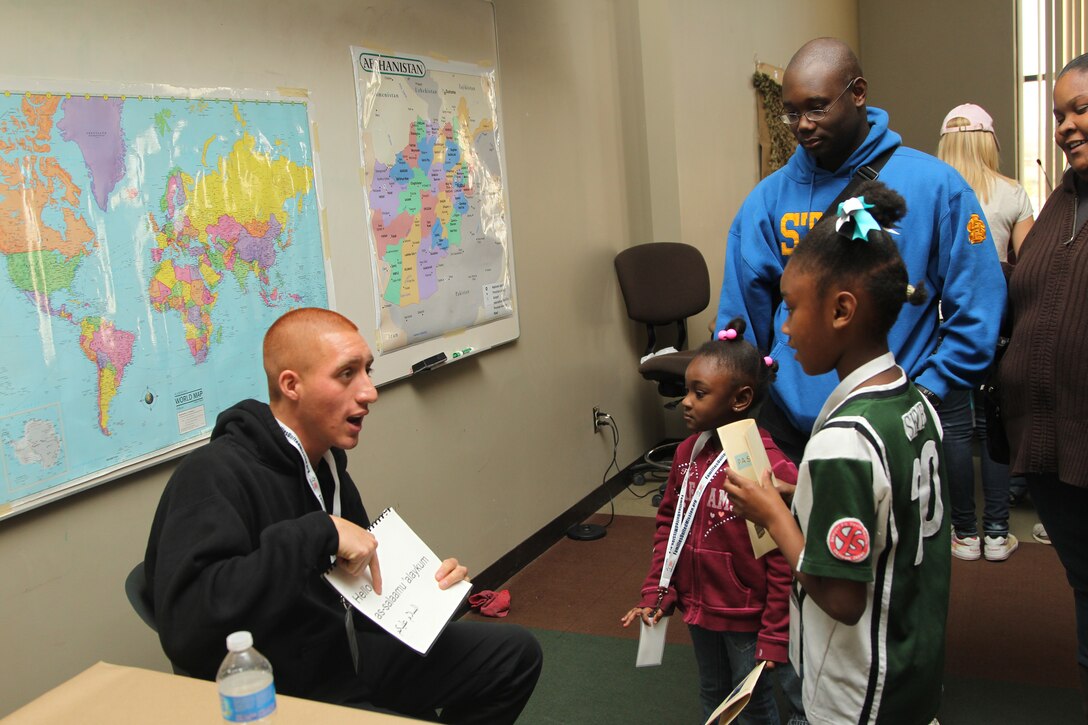 Lance Cpl. Chacoi Jorge, heavy equipment mechanic, Combat Logistics Battalion 7, teaches Dari to children Mya and Skye as their father, Staff Sgt. Thomas Winson, staff noncommissioned officer in charge, Support Company, 3rd Combat Engineer Battalion, looks on during the Camp Desert Kids program Dec. 3, 2011.