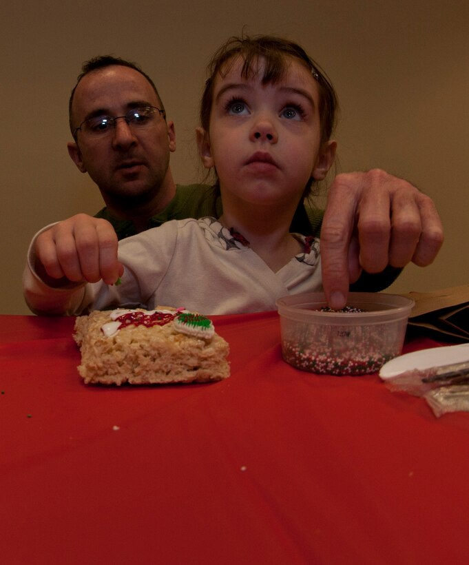 Serenity,  five, daughter of 345th Maintenance Squadron maintainer, Travis Hurst, puts sprinkles on her rice krispie treat during the 403rd Wing's Childrens' Christmas Party Dec. 10. (U.S. Air Force photo by Capt. J. Justin Pearce)