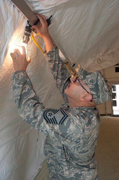Air Force Senior Master Sgt. Edward Berrios,136th Airlift Wing Civil Engineers Squadron, Texas Air National Guard, adjusts tent lighting during the construction of the tent, Dec. 10, 2011. Berrios supervised the construction of 3 tents for Operational Readiness Exercises held early next year. (Air National Guard photo by Tech. Sgt. Charles Hatton) 