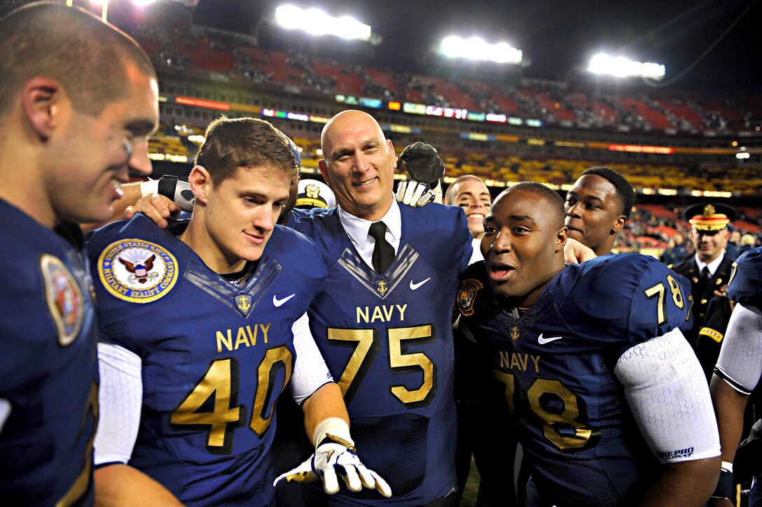 Army Chief of Staff Gen. Raymond T. Odierno, wearing a Navy football jersey, poses with the winning Midshipmen after finishing on the losing side of the Army-Navy wager about the outcome of the Army-Navy football game on FedEx Field in Landover, Md., Dec. 10, 2011. The Midshipmen defeated the Black Knights 27-21.
