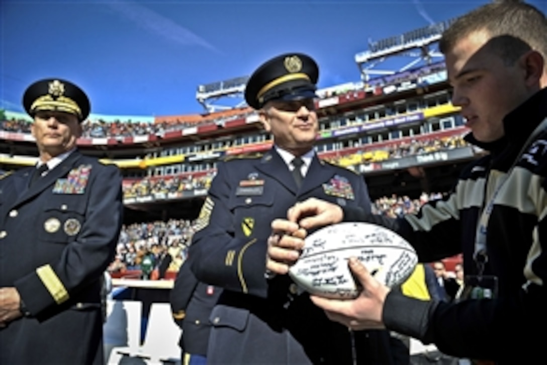 Army Sgt. Maj. Raymond F. Chandler III, center, signs the Army Black Knights' football before the start of the Army-Navy game on FedEx Field in Landover, Md., Dec. 10, 2011. 