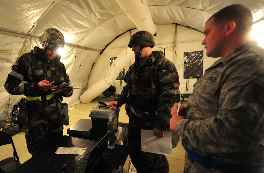 U.S. Air Force Tech. Sgt. Daniel Fleig, 23rd Comptroller Squadron budget analyst, left, helps customers during a phase II operational readiness exercise at Moody Air Force Base, Ga., Dec. 8, 2011. The finance office funds all day-to-day operations and supports service members with their pay and entitlements. (U.S. Air Force photo by Staff Sgt. Stephanie Mancha/Released) 
