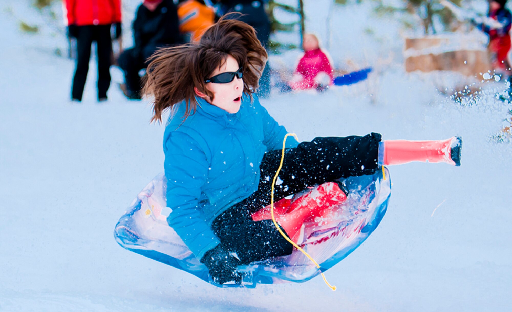 ALTERNATE ENDINGS: Sliding downhill is an exhilarating winter sport. People of all ages can participate, and use all kinds of containers, from large toboggans to plastic disks or even cardboard boxes. But accidental injuries from sledding are surprisingly common despite snow’s cushioning effect. (Photo by Tech. Sgt. Samuel Bendet)