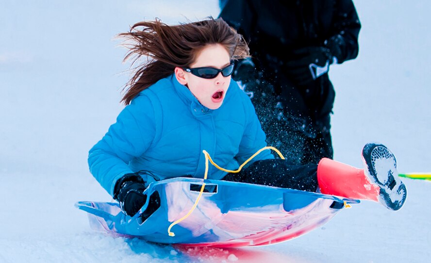 ALTERNATE ENDINGS: Sliding downhill is an exhilarating winter sport. People of all ages can participate, and use all kinds of containers, from large toboggans to plastic disks or even cardboard boxes. But accidental injuries from sledding are surprisingly common despite snow’s cushioning effect. (Photo by Tech. Sgt. Samuel Bendet)