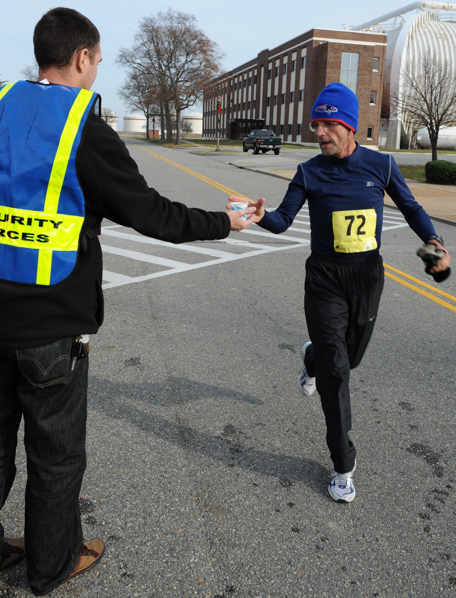 U.S. Air Force Senior Airman Jonathan McClenny, Air Combat Command A3 weapons system administrator, hands water to retired Master Sgt. Kevin Barry at the 7-mile marker during the “Race ‘Round the Base” at Langley Air Force Base, Va., Dec. 10, 2011. Volunteers set up water stations to keep runners hydrated and motivate participants. (U.S. Air Force photo by Airman 1st Class Teresa Cleveland/Released) 