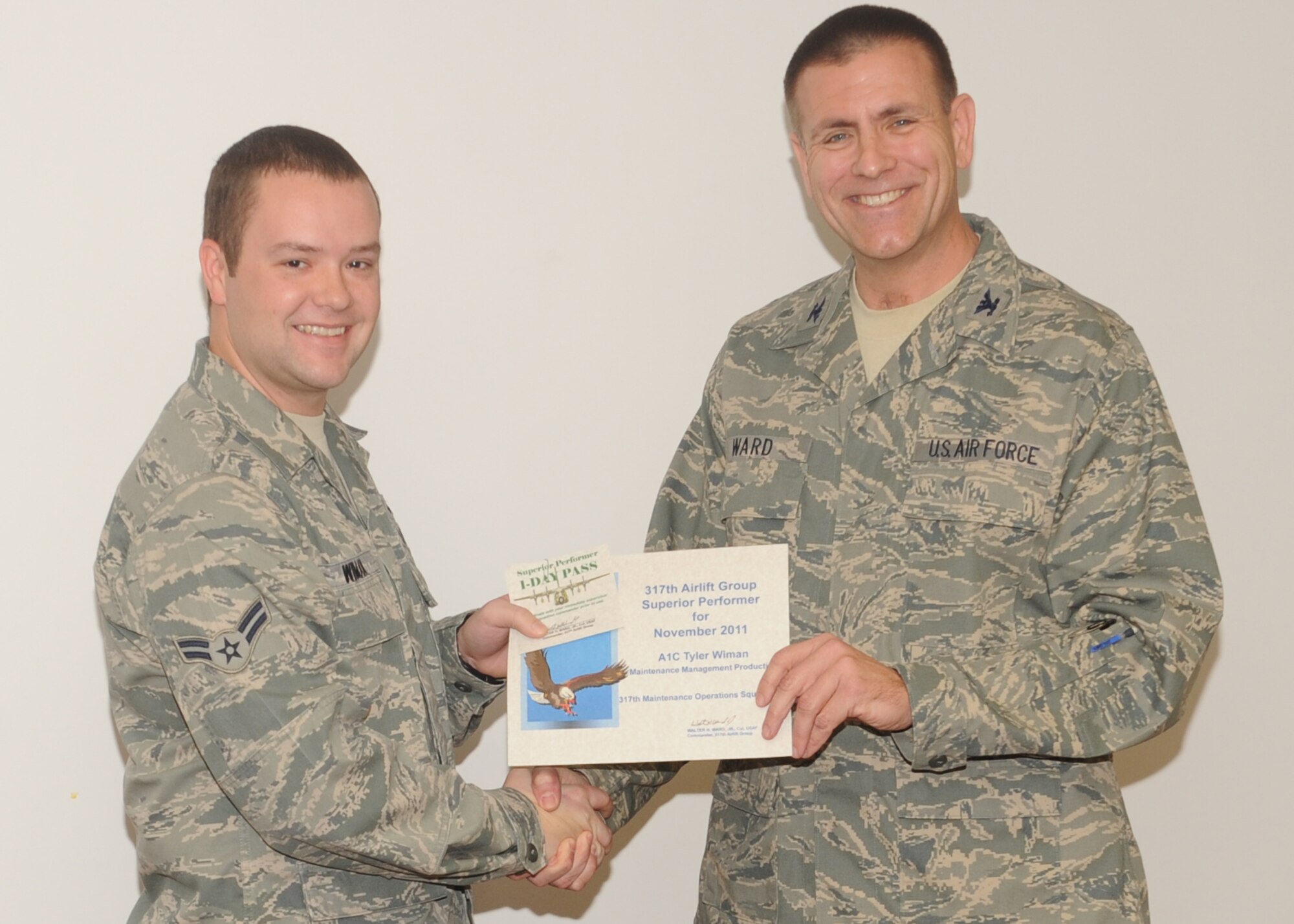 Col. Walter Ward, 317th Airlift Group commander, presents Airman 1st Class Tyler Wiman, 317th Maintenance Operations Squadron, with the superior performer award for the wing staff agencies Dec. 8, 2011, at Dyess Air Force Base, Texas. Every month each group selects a person or team who has shown superior performance to be recognized in front of wing leadership. (U.S. Air Force photo by Airman 1st Class Jonathan Stefanko/ Released)