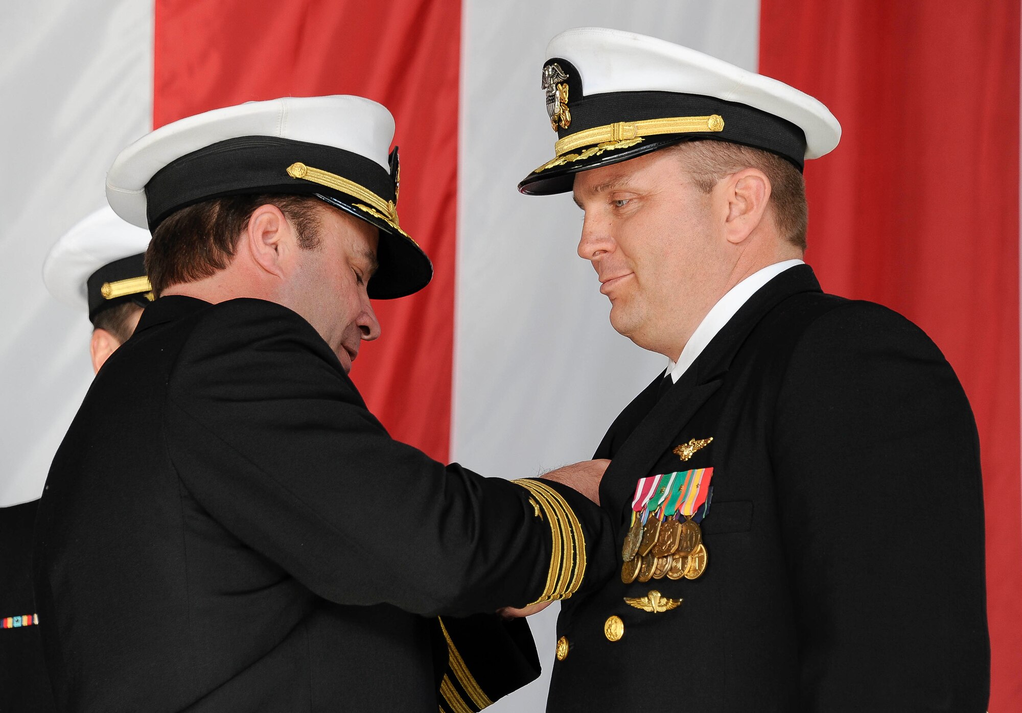 Commander Wade Robertson, outgoing commanding officer of Fleet Logistics Support Squadron 52, pins the command at sea pin onto Commander Ralph Dewalt II, incoming Commanding officer, as a sign of his leadership responsibilities incurred with his new position Dec. 3 here. VR-52‘s mission is to provide around-the-clock, responsive , flexible and rapidly-deployable air logistics support required to sustain combat operations at sea. (U.S Air Force photo by Airman Ryan Throneberry/Released)