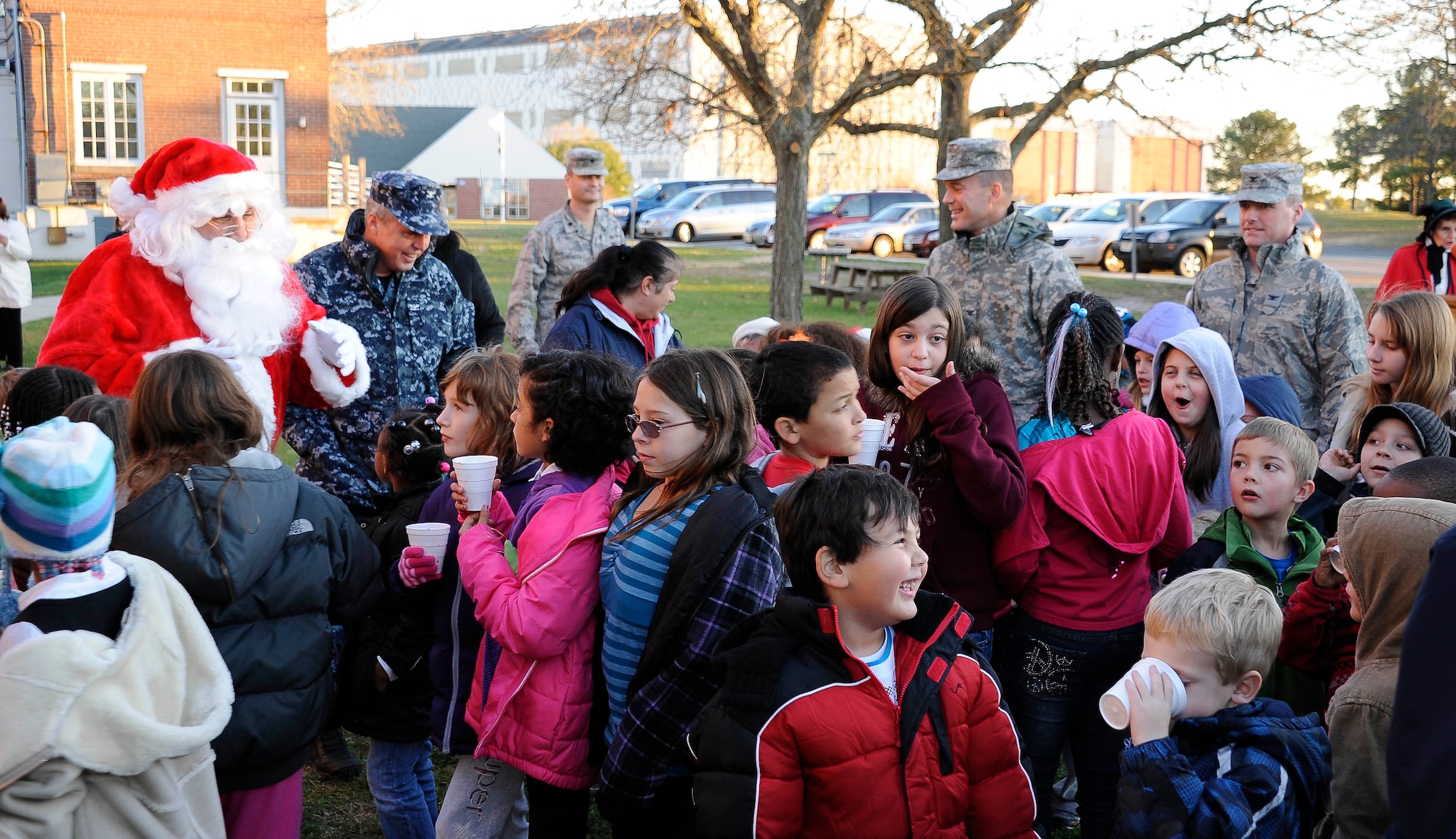 Santa, along with base leadership, greets Joint Base McGuire-Dix-Lakehurst children after the lighting of the tree in front of Command Headquarters on Lakehurst Dec. 1. Hot chocolate and cookies were served to get everyone into the holiday spirit. Children visited with Santa and shared their Christmas wish list before receiving a candy cane from Mrs. Claus. (U.S Air Force photo by Airman Ryan Throneberry/Released)