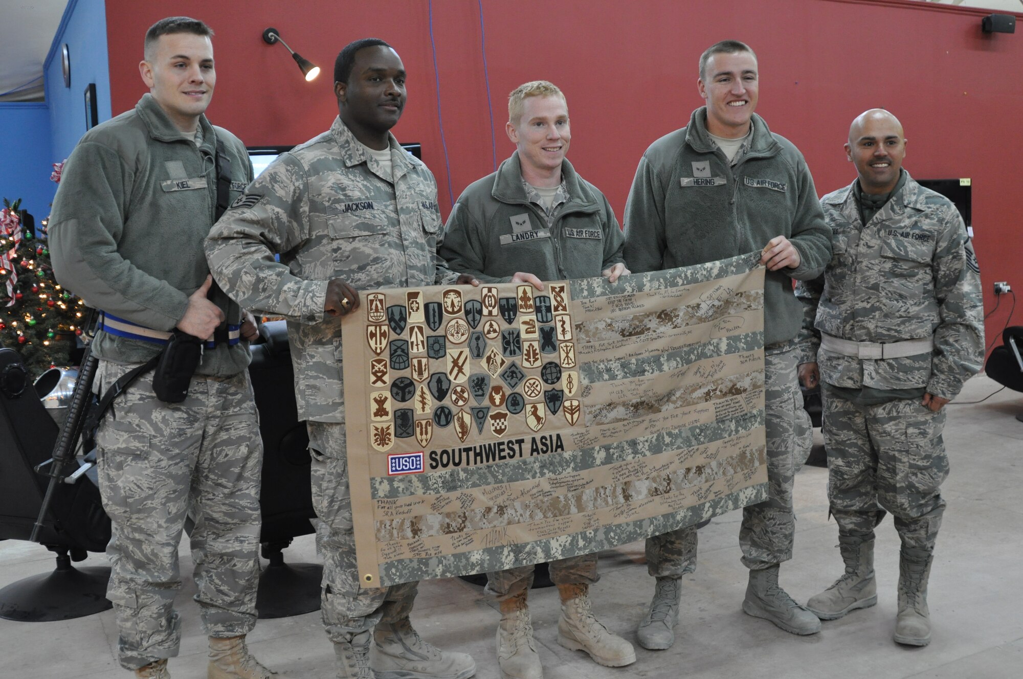 KANDAHAR AIRFIELD, Afghanistan -- From left, Senior Airman Justin Kiel, Staff Sgt. Jamison Jackson, Airman 1st Class Colin Landry, Airman 1st Class Marcus Hering, and Master Sgt. Pedro Torres from the 451st Air Expeditionary Wing sign a USO Southwest Asia quilt after participating in a Pro vs. GI Joe event at USO Kandahar Dec. 6, 2011. The Airmen played the Call of Duty video game against Miami Dolphins players Nate Garner and Charles Clay via Internet and webcam connections. (U.S. Air Force photo by Capt. Passion Julinsey)