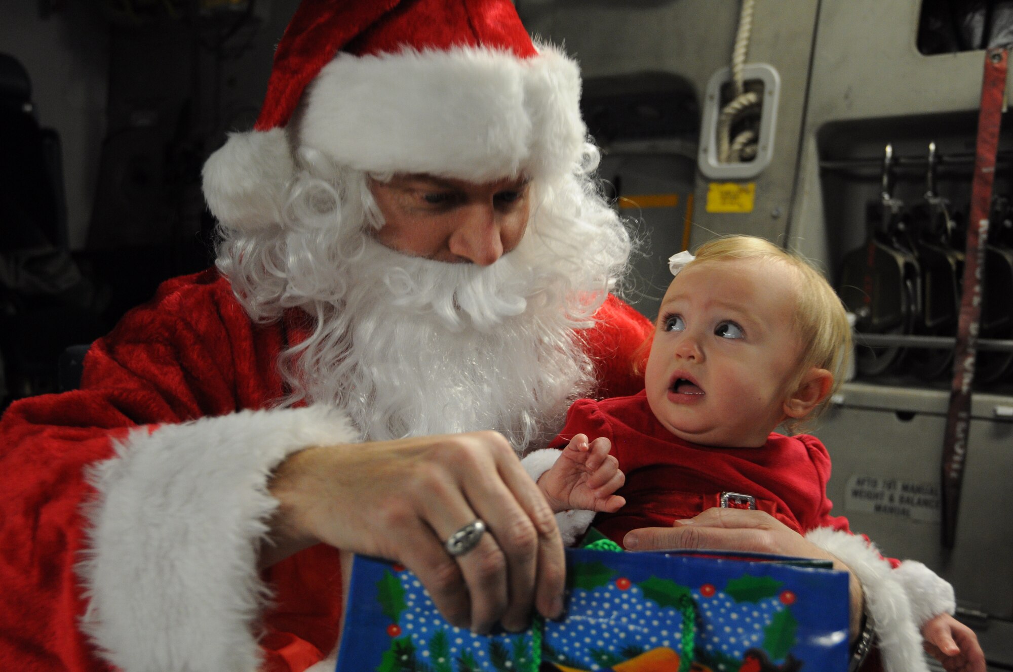 Santa Claus delivers a present to his adorable new friend Dec. 10, 2011 at Joint Base Charleston, S.C.; however, this pretty little girl is still trying to figure out what this Santa stuff is all about. While visiting Charleston, Santa spent time with friends and families of the 315th Airlift Wing. (U.S. Air Force photo/ Staff Sgt. Shane Ellis)