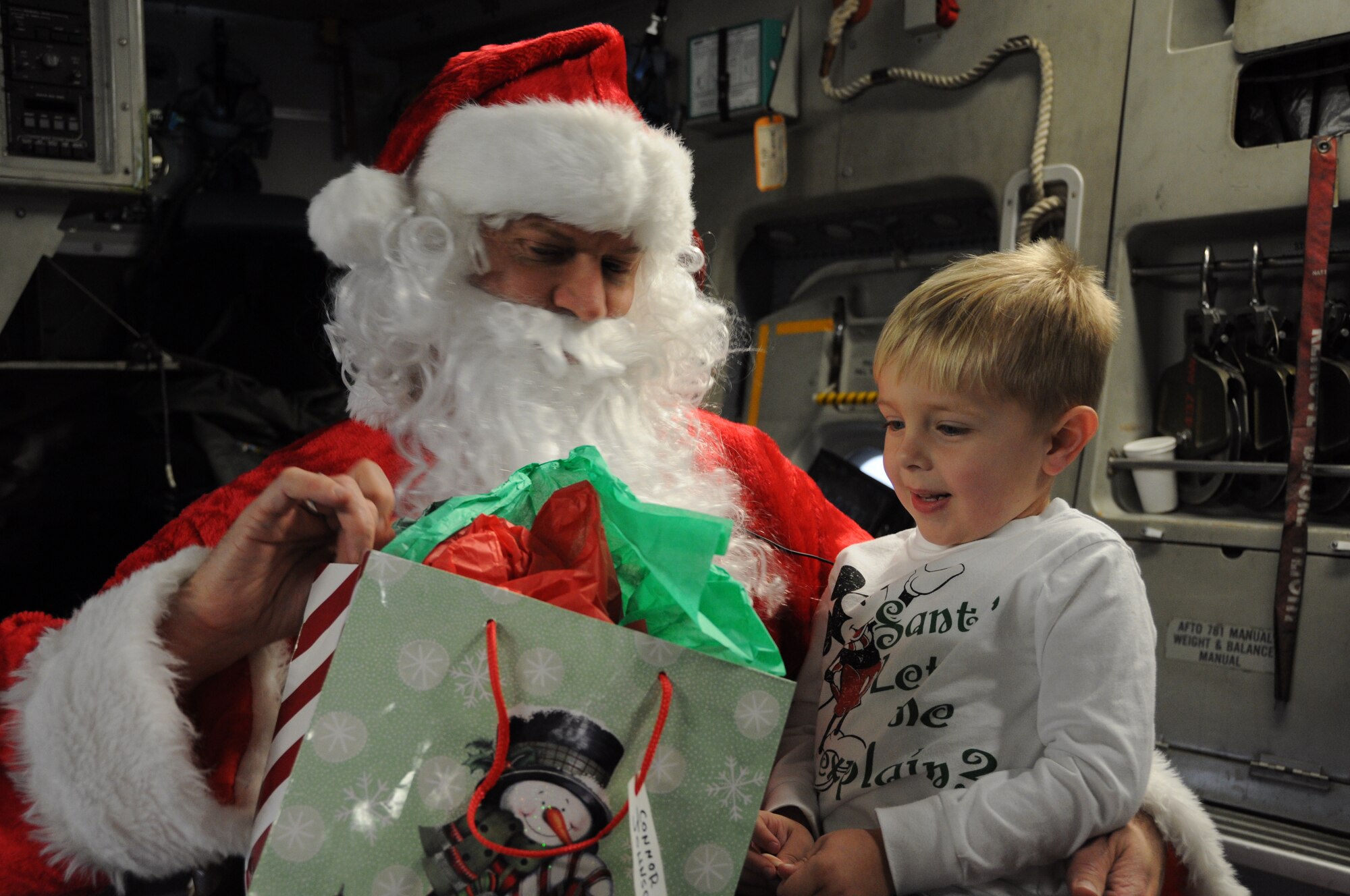 Santa Claus delivers a present to one happy little boy Dec. 10, 2011 at Joint Base Charleston, S.C. Santa set up his workshop in the cargo compartment of a C-17 Globemaster III aircraft which is well known for delivering valuable cargo around the globe. (U.S. Air Force photo/ Staff Sgt. Shane Ellis)