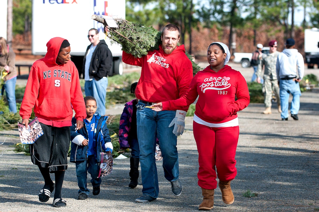 Daniel Bryan, World Wrestling Entertainment wrestler, helps a family carry a Christmas tree to their car during a Trees for Troops event on Fort Bragg, N.C., Dec 10, 2011.