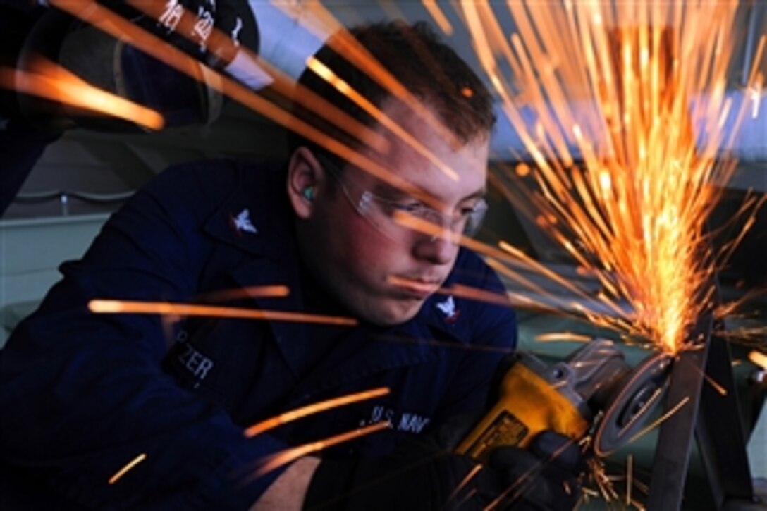 U.S. Navy Petty Officer 3rd Class Nicholas Pitzer grinds the frame of a table in the recreation room aboard the amphibious assault ship USS Makin Island (LHD-8) underway in the Pacific Ocean on Dec. 6, 2011.  Pitzer is a hull maintenance technician.  
