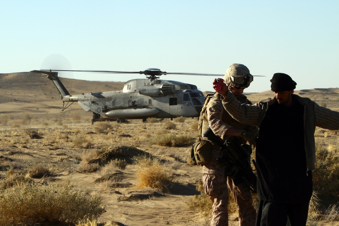 U.S. Marine Sgt. Alston Hays, an air interdiction force team member with Regimental Combat Team 5, searches a local man during an air interdiction force mission here, Dec. 7. The AIF mission was conducted in support of an Afghan Border Police led clearing operation in Khan-Neshin. During the mission, Marines and sailors from Charlie Co., 1/25, and 2nd Bn., 11th Marines, circled above, searching for suspicious vehicles or personnel. The AIF plays a unique role with Regimental Combat Team 5’s counter-insurgency operations in southern Helmand.