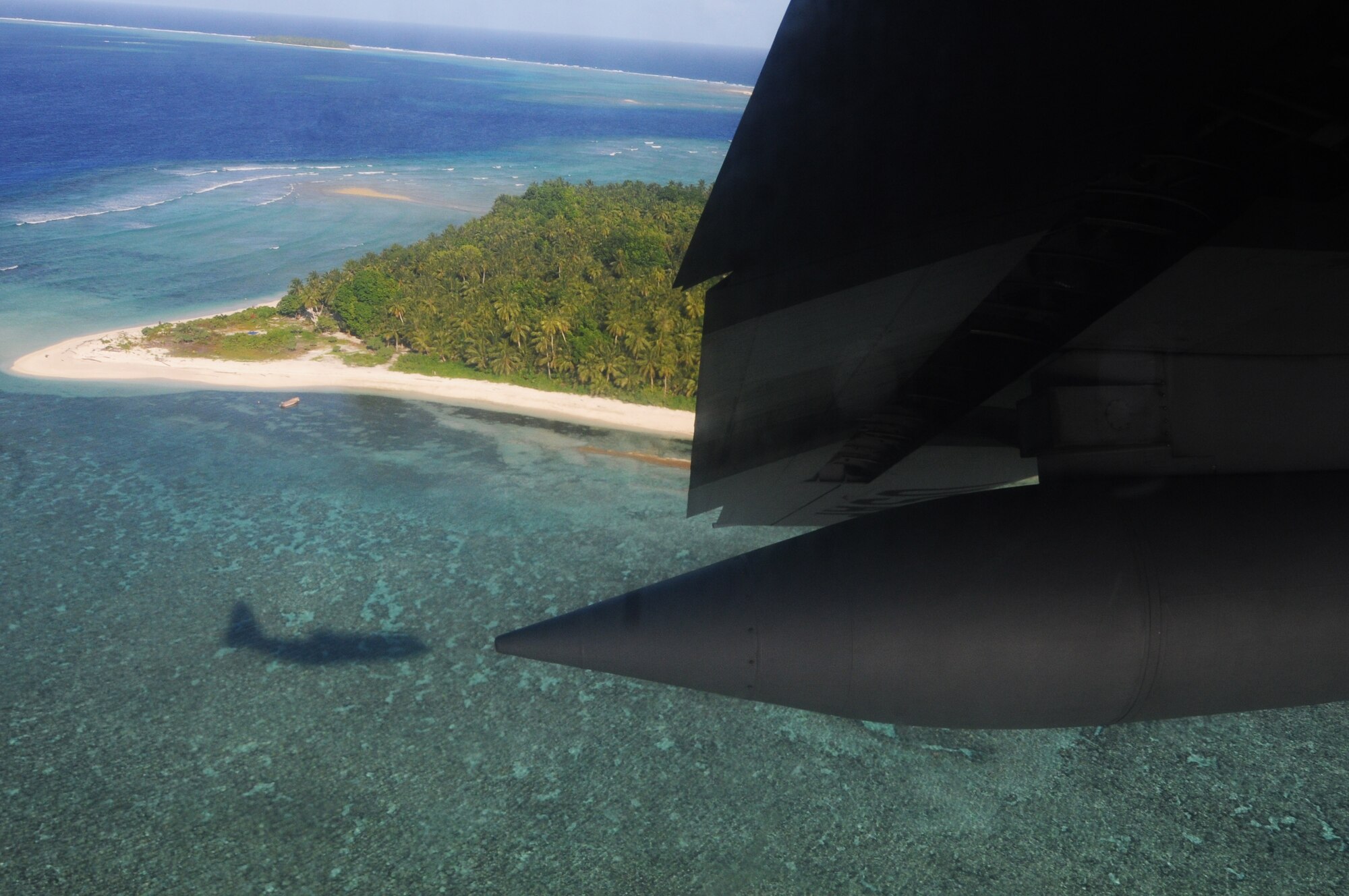 ANDERSEN AIR FORCE BASE, Guam - The C-130 is silhouetted on the ocean while it completes a fly-by ensuring safe arrival of the Operation Christmas Drop care package to Ngulu Island of the Micronesian Islands, Dec. 12. The pallet was a box full of goodies for the islanders containing school supplies, toys, medical supplies and common day items. (U.S. Air Force photo/Senior Airman Carlin Leslie)