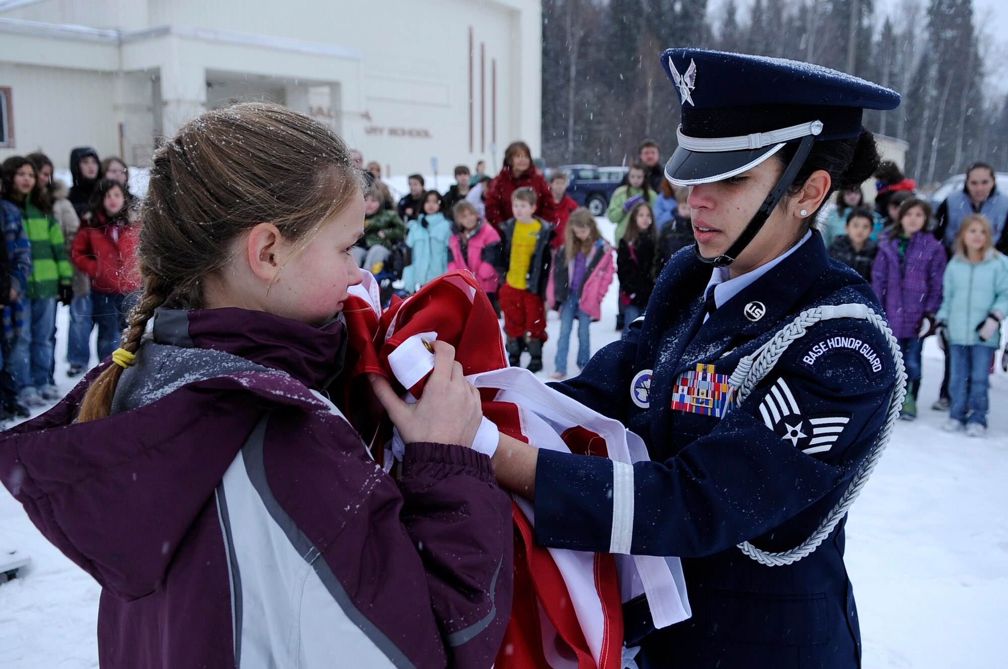 U.S. Air Force Staff Sgt. Frances Hernandez helps a Salcha Elementary student fold the U.S. flag Dec. 9, 2011, Salcha, Alaska. Hernandez is an honor guardsman and a logistics planner assigned to the 354th Logistics Readiness Squadron. Eielson honor guardsmen educated students on the importance of proper flag folding during reveille and retreat. (U.S. Air Force photo by Staff Sgt. Jim Araos/Released)