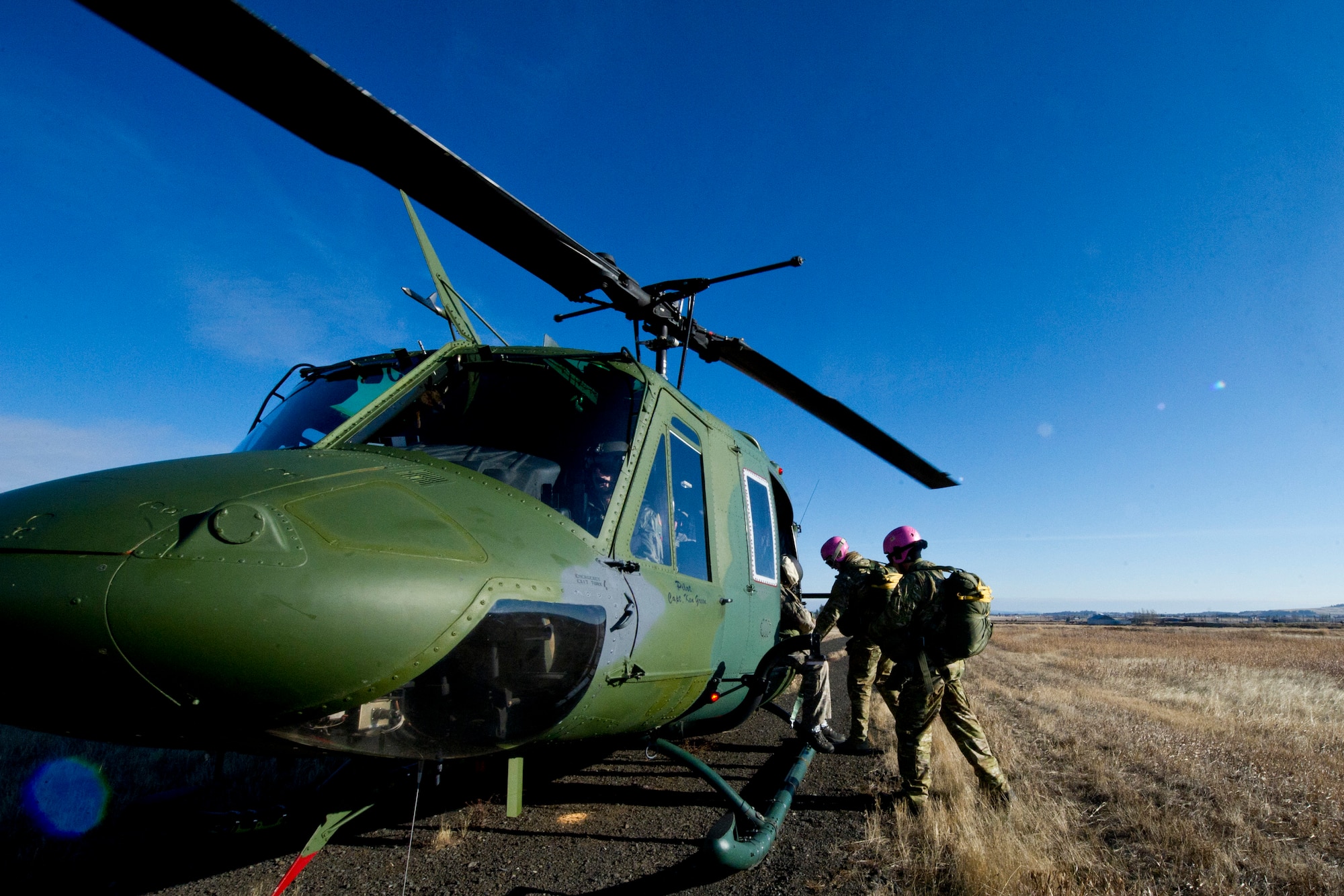 Members of the Survival, Evasion, Resistance and Escape School prepare to ascend on a UH-1 Huey helicopter at their training field on Fairchild Dec. 5. SERE training consists of learning to adapt to all biomes and their associated weather conditions, and surviving various captivity situations.  One aspect of that training involves being able to properly parachute safely to the ground in any emergency. (U.S. Air Force photo/Airman 1st Class Taylor Curry)