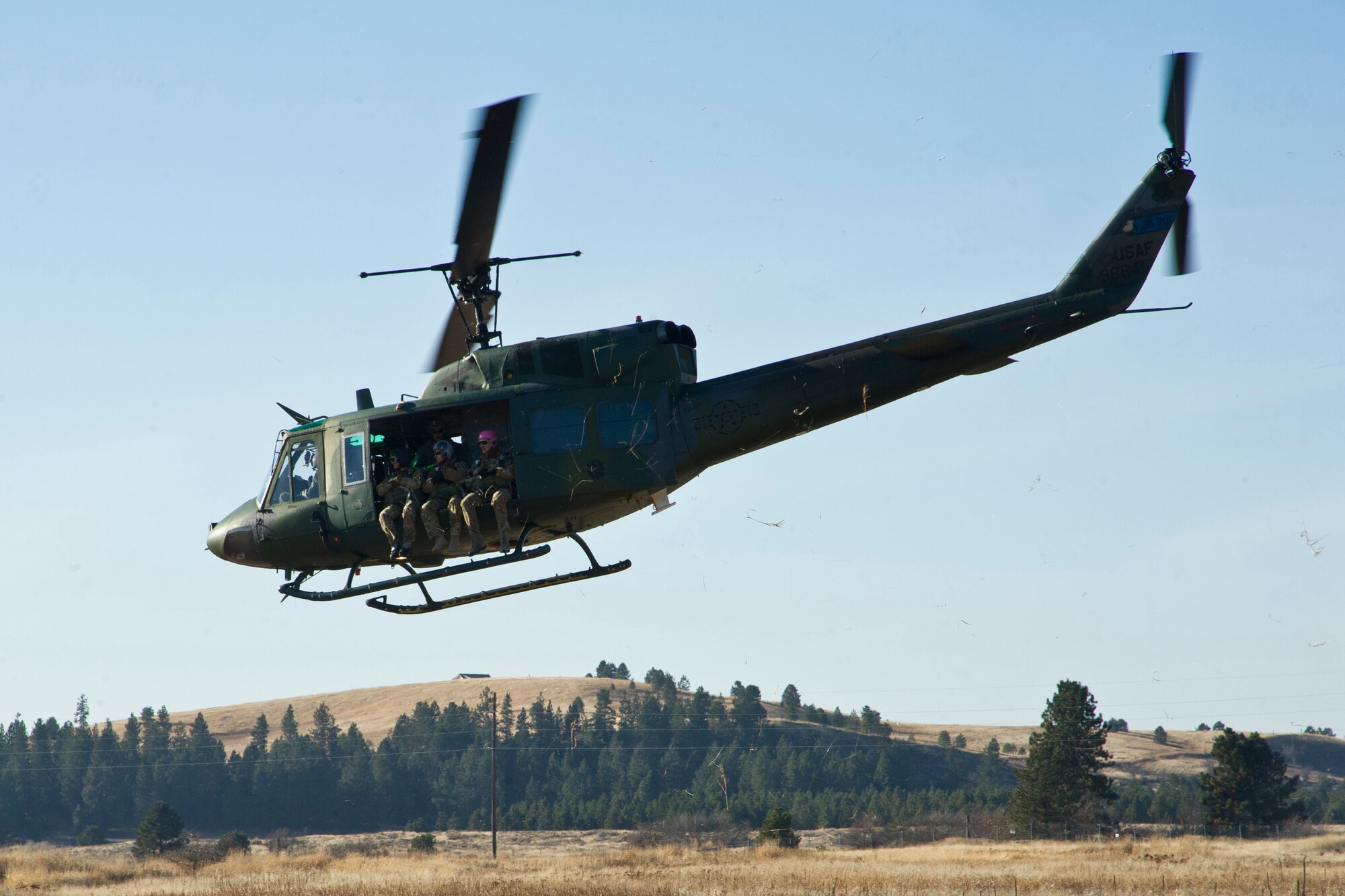 Members of the Survival, Evasion, Resistance and Escape School prepare to ascend on a UH-1 Huey helicopter at their training field on Fairchild Dec. 5. SERE training consists of learning to adapt to all biomes and their associated weather conditions, and surviving various captivity situations.  One aspect of that training involves being able to properly parachute safely to the ground in any emergency. (U.S. Air Force photo/Airman 1st Class Taylor Curry)