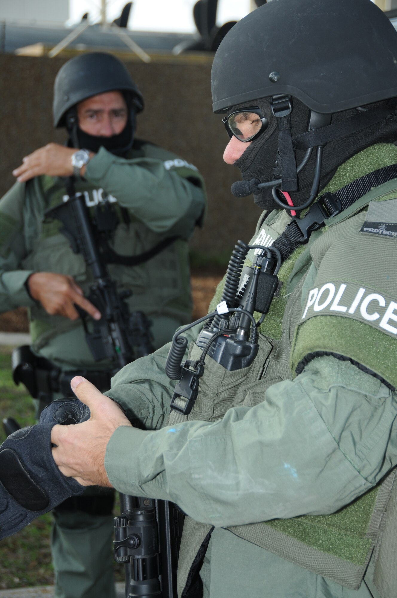 During an anti-hijacking exercise on the flightline at Keesler Air Force Base, Miss., Dec. 12, 2011, Biloxi Police Department Special Response Team member Sgt. Rick Allen dons his gloves in preparation for the rehearsal of the tactical assault while Officer David Bell demonstrates the one-hand signals that will be practiced during the rehearsal.  (U.S. Air Force photo by Kemberly Groue)