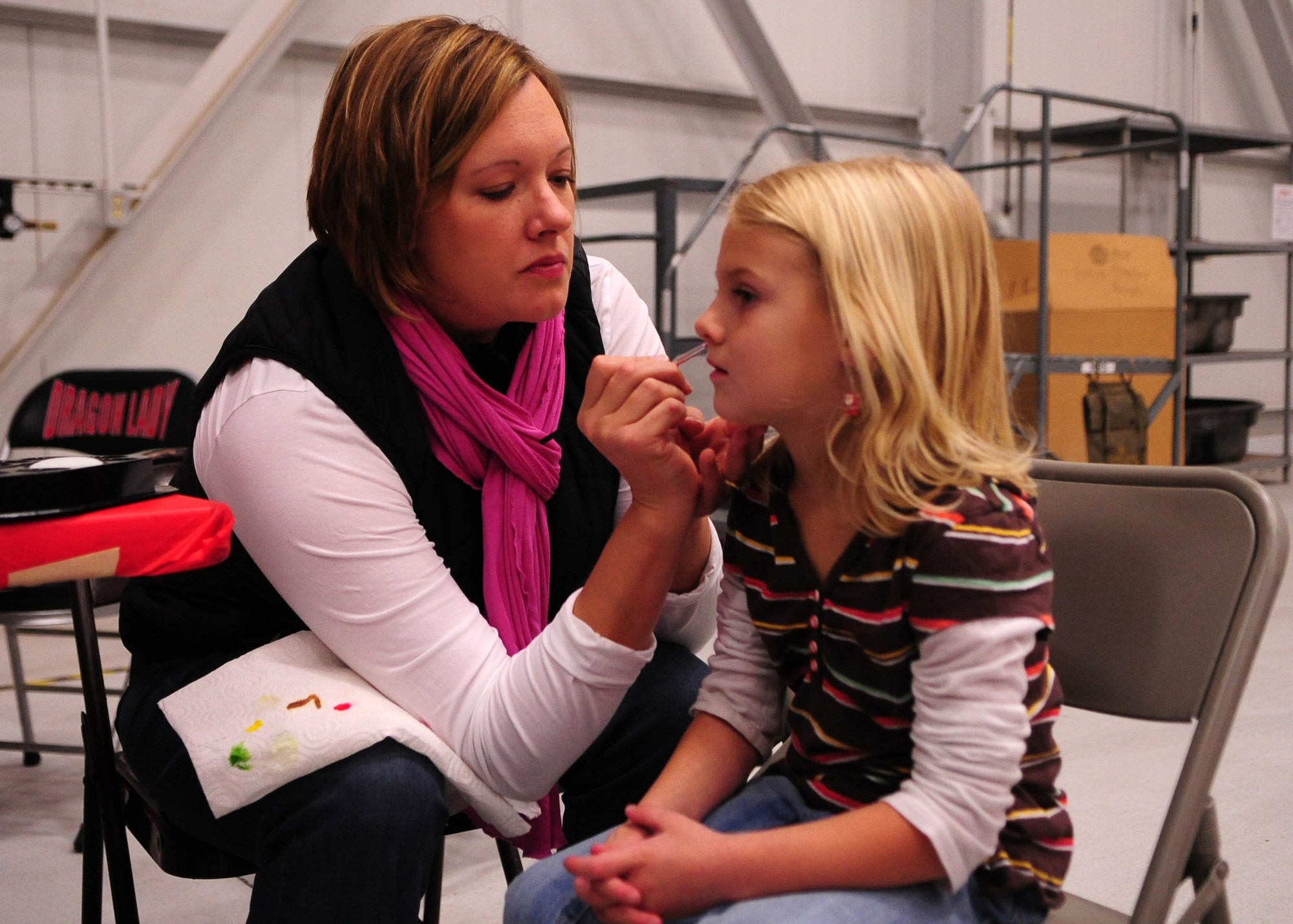 Jenny Yates, a member of Beale's Officer Spouses Club, paints the face of a Beale youth at Dock 6, Beale AFB, Calif., during the Children's Holiday Party Dec. 10. More than 75 volunteers from Beale and the surrounding community worked since before Halloween to make the celebration possible. (U.S. Air Force photo by Senior Airman Shawn Nickel/Released)