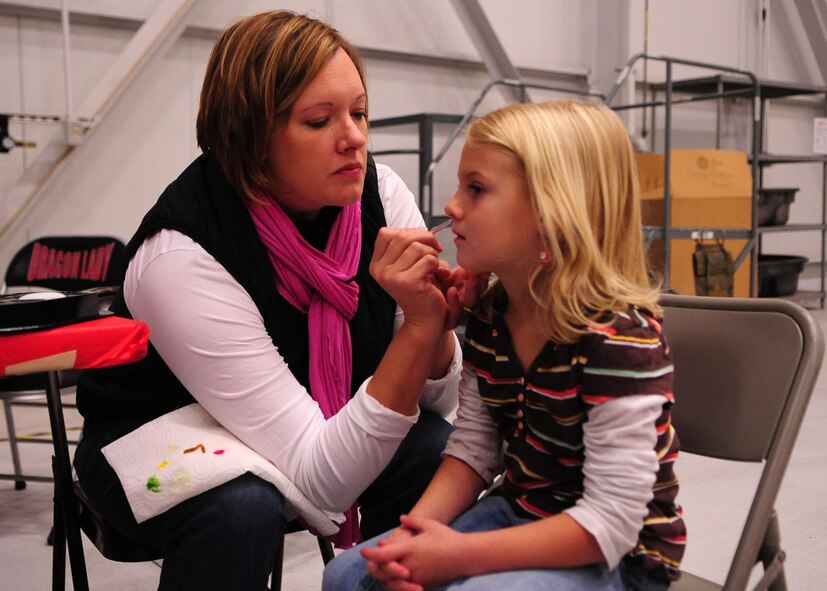 Jenny Yates, a member of Beale's Officer Spouses Club, paints the face of a Beale youth at Dock 6, Beale AFB, Calif., during the Children's Holiday Party Dec. 10. More than 75 volunteers from Beale and the surrounding community worked since before Halloween to make the celebration possible. (U.S. Air Force photo by Senior Airman Shawn Nickel/Released)