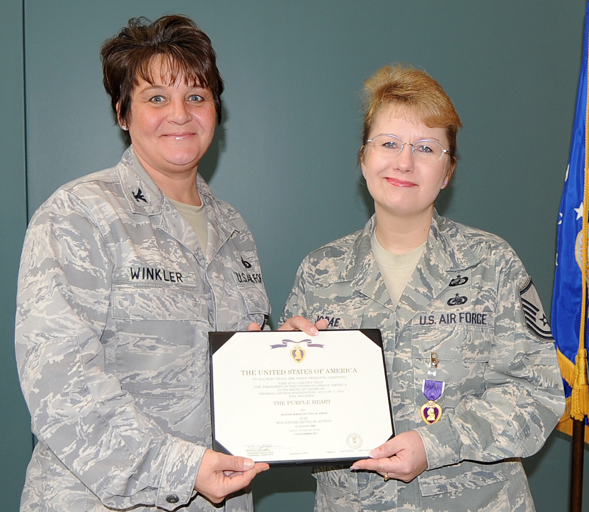 Col. Anne Winkler, 4th Mission Support Group commander, presents Master Sgt. Tina Jorae, 4th Contracting Squadron contract specialist, with a Purple Heart medal at Seymour Johnson Air Force Base, N.C., Dec. 9, 2011. Jorae received the medal for wounds received when a suicide bomber drove a vehicle borne improvised explosive device into her living quarters while deployed to Kabul, Afghanistan, Aug. 15, 2009. Jorae displayed selfless act of courage during the attack by clearing the building she was residing in and carrying a traumatized and injured Solider to a medical facility after the attack. (U.S. Air Force photo by Senior Airman Gino Reyes)