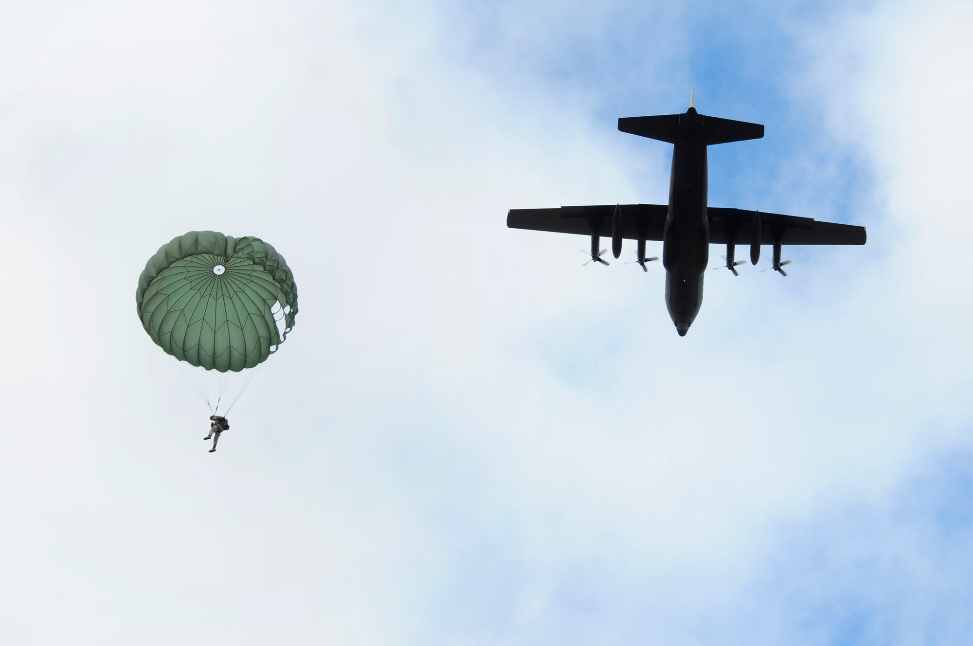 A member of the 435th Security Forces Squadron glides into a designated drop zone while a C-130J Super Hercules passes during an off-site training in Zaragoza, Spain, Dec. 12, 2011. The OST consisted of a 90 member team and two aircraft, all assembled to enhance interoperability between U.S. and Spanish air forces as well as build partnerships between the two countries. (U.S. Air Force photo by Senior Airman Katherine Holt)