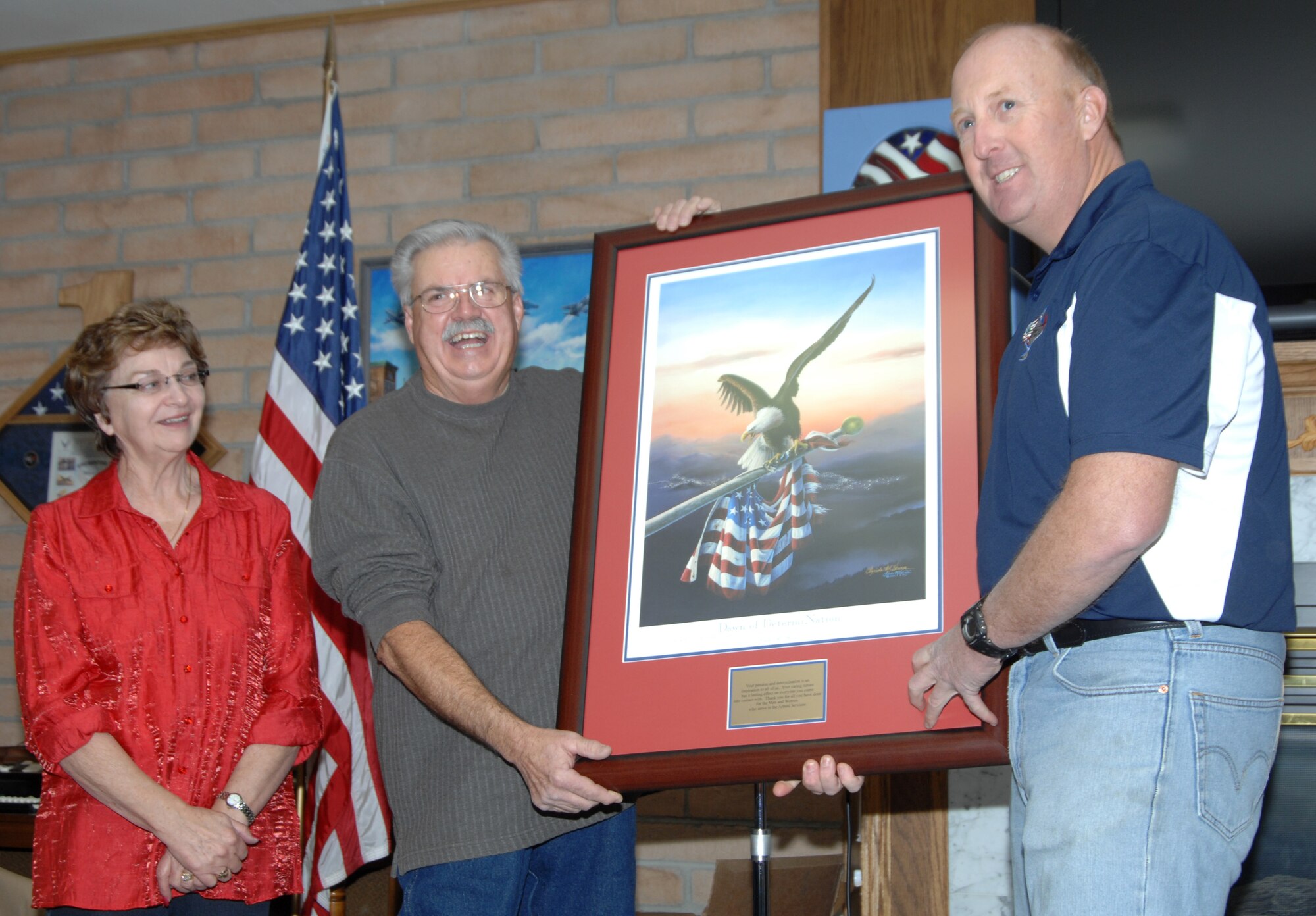 From left, Rita Albers, Silvercrest II estates fundraising manager, stands next to Don Garner, Silvercrest II estates manager, who accepts a painting commemorating 10 years of donations and support Dec.10, 2011 from Master Sgt. Mikel Caraway, 366th Maintenance Operations Squadron first sergeant and Operation Warmheart president. The donations and supplies collected from Silvercrest II Estates retirement community are dispersed through Operation Warmheart to military families from Mountain Home Air Force Base, Idaho, who may be dealing with financial hardship. (U.S. Air Force photo by Senior Airman Benjamin Sutton) 