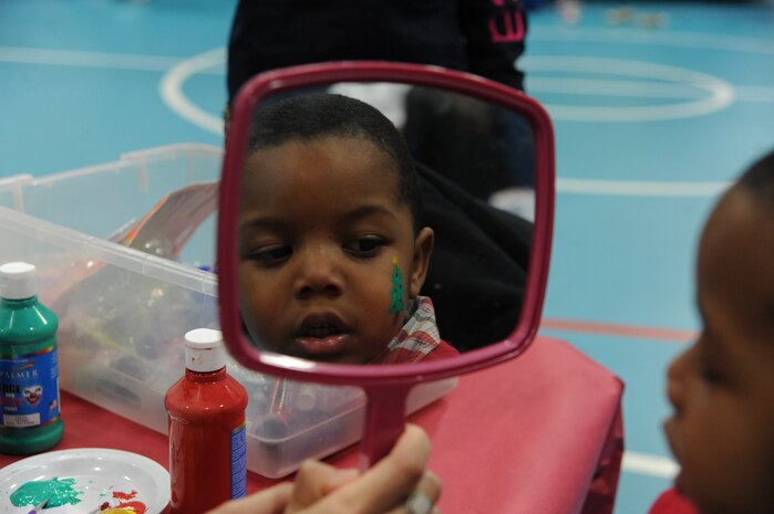 Vincent Cooper, nephew of Retired Master Sgt. Theresa Green's nephew, Vincent Cooper, looks at the Christmas tree painted on his face at the Youth Holiday Party at Joint Base Charleston - Air Base Dec. 10. The Youth Center put together a Holiday Party for kids of all ages and had fun stations including: "VanDoren" the Magician, a bounce house, dart throwing, mini-golf, face painting, free food and a surprise appearance from Santa Claus. (U.S. Air Force photo/Airmen 1st Class Ashlee Galloway)