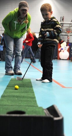 Captain Brent Robbins son Michael, hits a golf ball at the Youth Holiday Party at Joint Base Charleston-Air Base Dec. 10. The Youth Center put together a Holiday Party for kids of all ages and had fun stations including: "VanDoren" the Magician, a bounce house, dart throwing, mini-golf, face painting, free food and a surprise appearance from Santa Claus. Robbins is from the 14th Airlift Squadron, 437th Airlift Wing. (U.S. Air Force photo/Airmen 1st Class Ashlee Galloway)