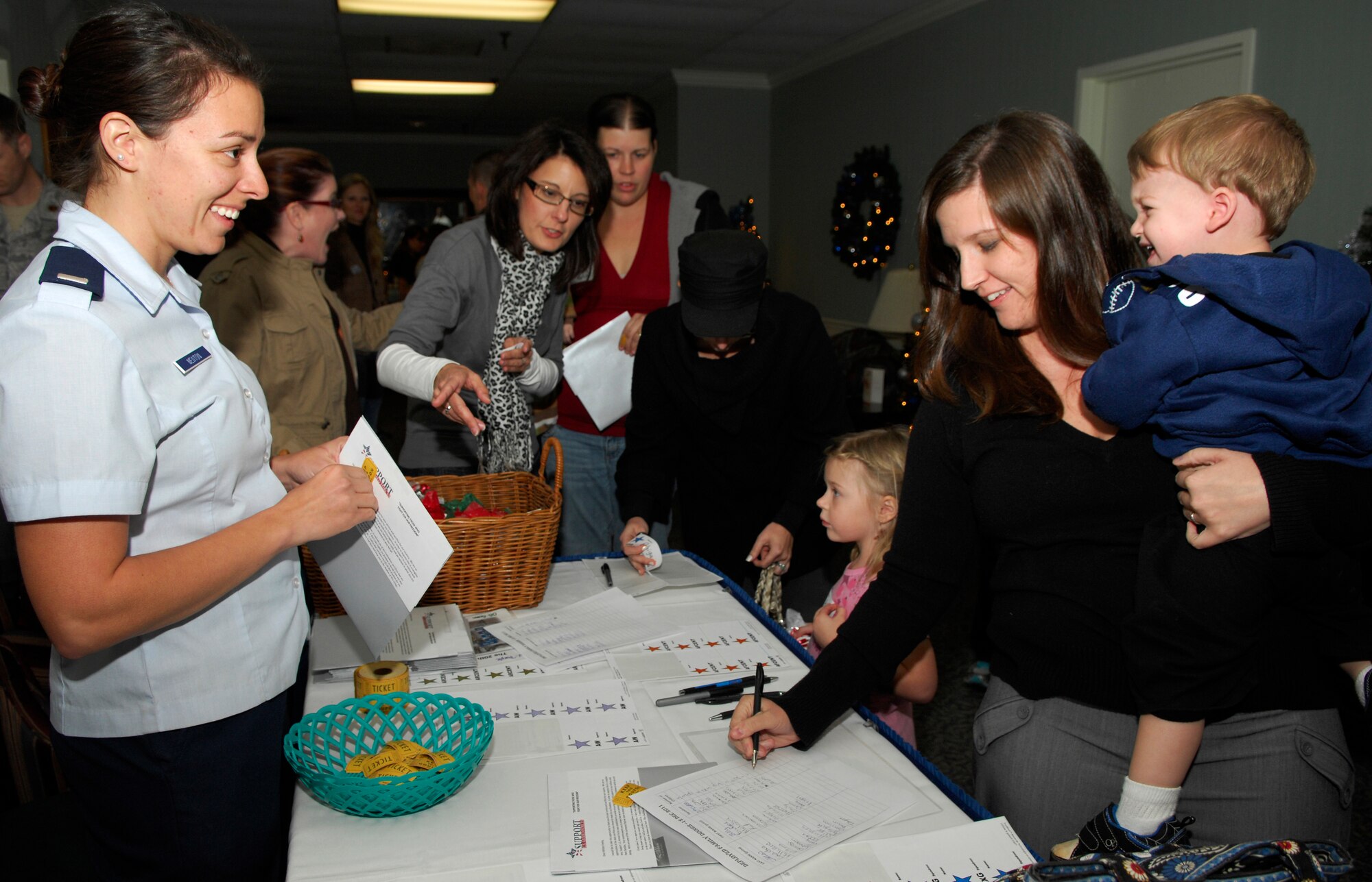 U.S. Air Force 1st Lt. Molly Newton, 20th Logistics Readiness Squadron deployment and distribution flight commander, welcomes families in with a smile at the deployed families' dinner Dec. 12, 2011, Shaw Air Force Base, S.C. The dinner was held at the Carolina Skies Club and offered a free family dinner, Christmas gifts and goodies to the children .  (U.S. Air Force photo by Airman 1st Class Ashley L. Gardner/ Released)
