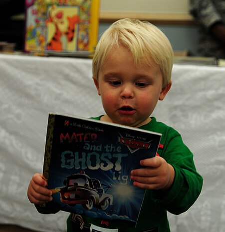 Jackson Wardle, son of Master Sgt, Jennifer Wardle, looks at a book he chose at the Book Fair held at the Child Development Center at Joint Base Charleston - Air Base Dec. 12.  More than 800 books were donated to the CDC by Barnes and Nobles customers. The drive was held to support military families and promote child literacy. Members of the First Six association volunteered to hand out the books to parents and children during drop-of and pick-up times at the CDC. Wardle is from the 437th Aerial Port Squadron. (U.S. Air Force photo/ Staff Sgt. Nicole Mickle0  