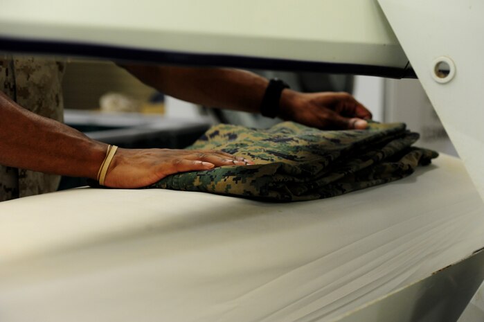 A prisoner presses a pair of pants while working in the laundry room inside the Naval Consolidated Brig Charleston at Joint Base Charleston - Weapons Station Sept. 20. Prisoners have the opportunity to participate in a variety of certification and trade programs including automotive repair, wood-working, metal fabrication, and the sail-loft shop where they learn  embroidery skills.These programs serve as  rehabilitation tools for the prisoners.   (U.S. Air Force photo/ Staff Sgt. Nicole Mickle) 