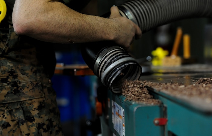 A prisoner cleans up wood shavings while working in the wood shop inside the Naval Consolidated Brig Charleston at Joint Base Charleston - Weapons Station Sept. 20.  Prisoners have the opportunity to participate in a variety of certification and trade programs including automotive repair, wood-working, metal fabrication, and the sail-loft shop where they learn embroidery skills. These programs serve as  rehabilitation tools for the prisoners.   (U.S. Air Force photo/ Staff Sgt. Nicole Mickle)  