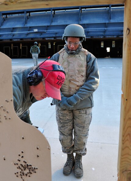 MINOT AIR FORCE BASE, N.D. – Staff Sgt. Joseph Haller, 5th Security Forces Squadron combat arms training and maintenance instructor, trains Airman 1st Class Daniela Toney, 5th Logistics Readiness Squadron transportation management, on qualifying firing procedures here, Dec. 8. CATM instructors are security forces personnel who train military members on weapon use. They also maintain and repair weapons in the security forces inventory. (U.S. Air Force photo/Senior Airman Desiree Esposito) 
